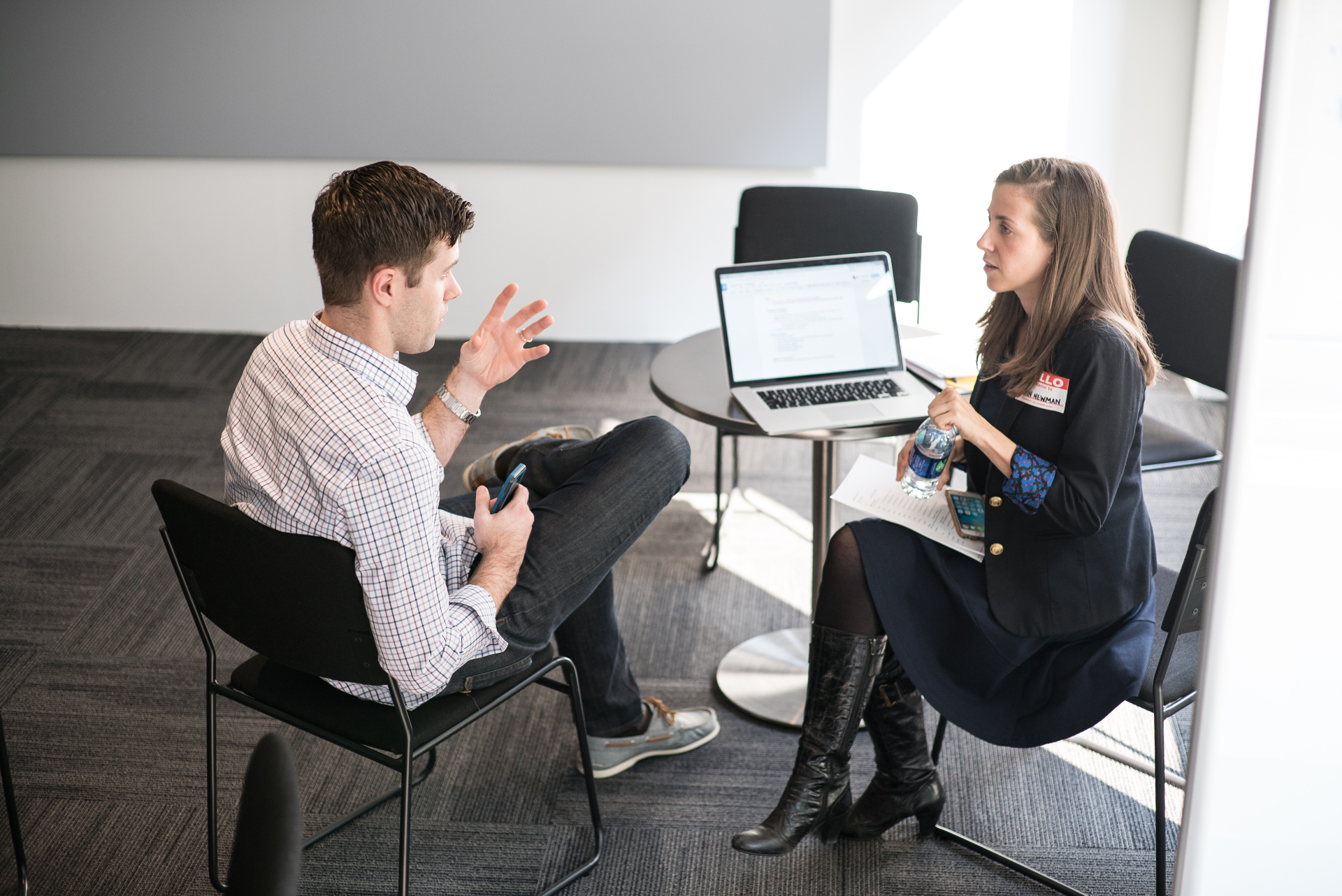A Huge researcher interviewing a participant one-on-one, both seated with a laptop on the table between them.